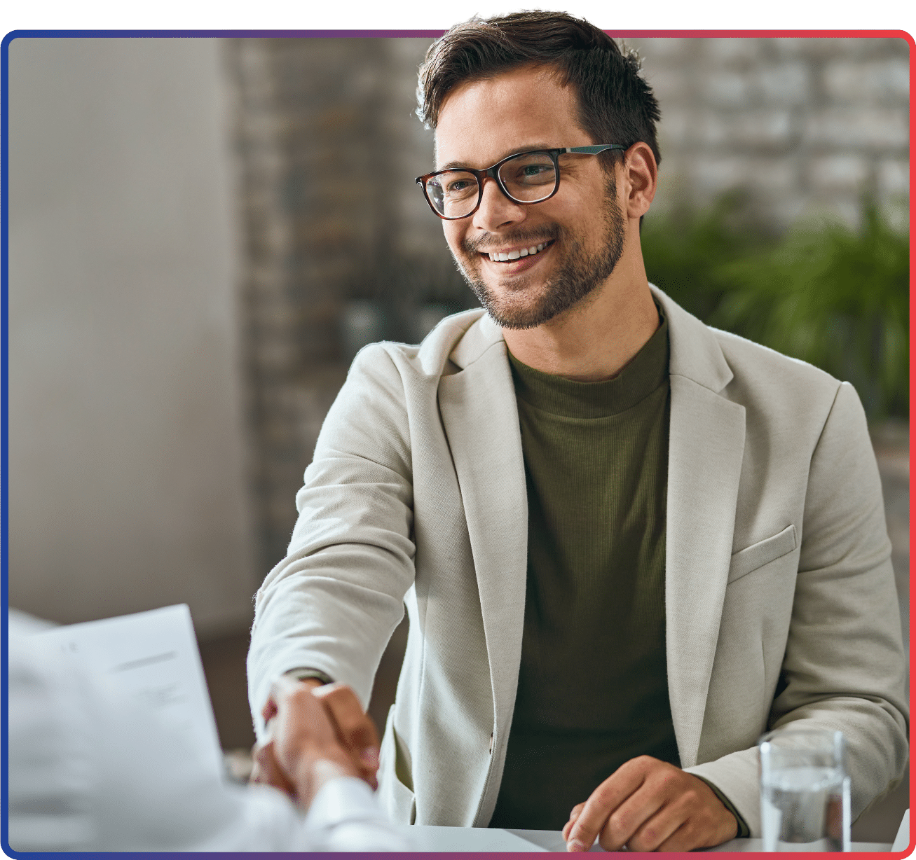 a smiling man wearing glasses and having a warm handshake